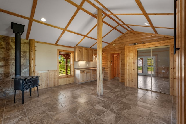 68 Bieler Ln, Sheridan, MT 59749 - unfurnished living room featuring lofted ceiling, healthy amount of natural light, wooden walls, a wood stove, and wainscoting