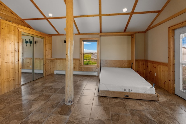 68 Bieler Ln, Sheridan, MT 59749 - unfurnished bedroom with vaulted ceiling, wood walls, a baseboard heating unit, wainscoting, and stone finish flooring