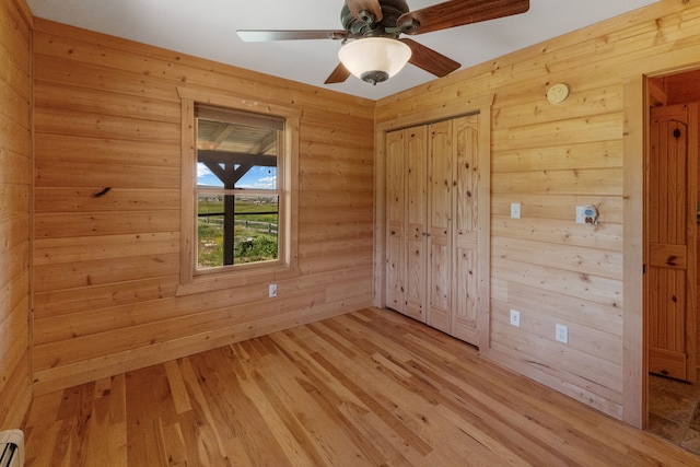 68 Bieler Ln, Sheridan, MT 59749 - empty room with a baseboard heating unit, wood walls, light wood-style floors, and ceiling fan