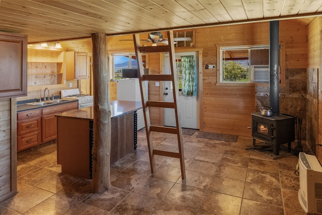 68 Bieler Ln, Sheridan, MT 59749 - kitchen featuring wooden walls, white range with gas cooktop, wooden ceiling, a wood stove, and dark countertops
