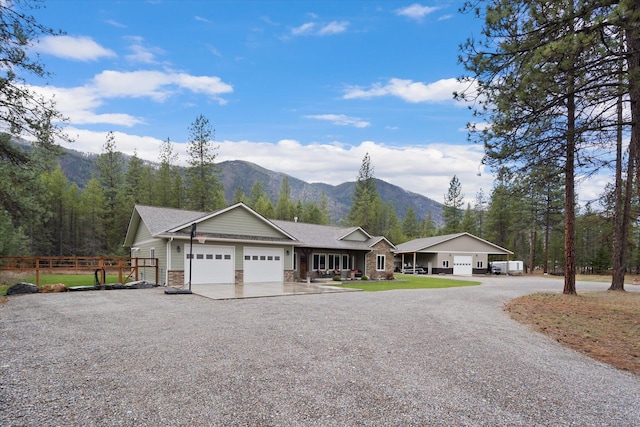 388 Cherry Creek Rd, Thompson Falls, MT 59873 - view of front of property featuring an attached garage, gravel driveway, stone siding, and a mountain view