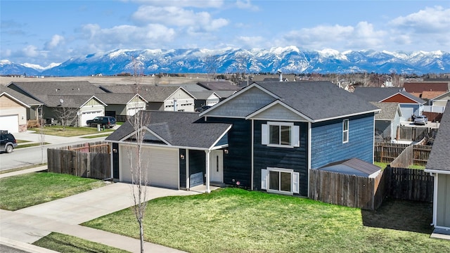 227 Jackson Peak Dr, Kalispell, MT 59901 - view of front of home with concrete driveway, a residential view, a mountain view, a front lawn, and fence