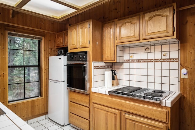 3700 Glen Lake Rd, Eureka, MT 59917 - kitchen featuring tile countertops, black oven, freestanding refrigerator, stainless steel electric stovetop, and tasteful backsplash