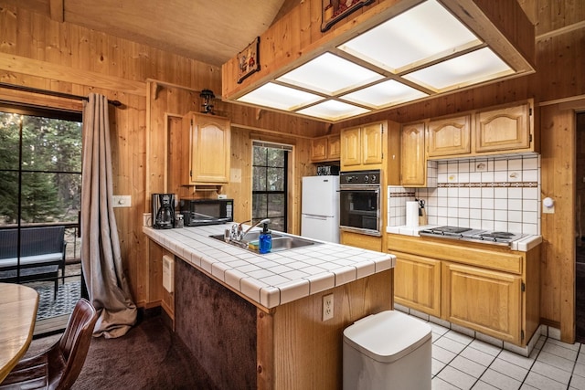 3700 Glen Lake Rd, Eureka, MT 59917 - kitchen with black appliances, wood walls, a peninsula, decorative backsplash, and tile counters