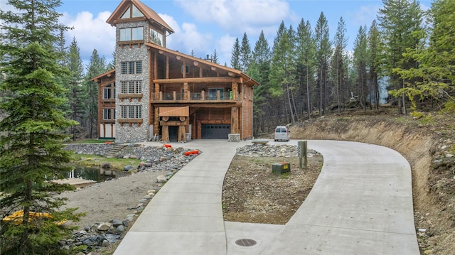 3700 Glen Lake Rd, Eureka, MT 59917 - view of front of home with stone siding, a garage, concrete driveway, and a balcony