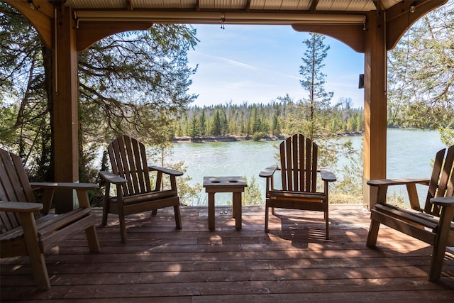 deck with a wooded view and a water view