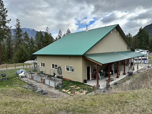 85 Osprey Dr E, Thompson Falls, MT 59873 - view of home's exterior featuring a vegetable garden, a patio, fence, metal roof, and a mountain view