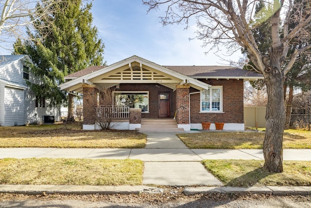 view of front of house with a porch, central air condition unit, fence, and brick siding