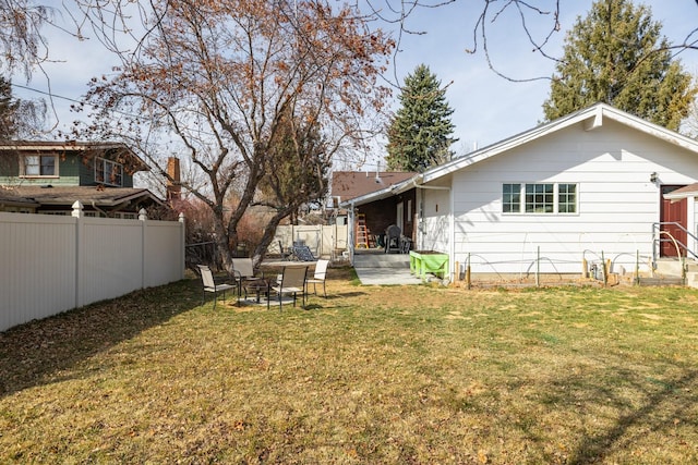 rear view of house with a fenced backyard, a patio, and a lawn