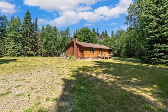 220 Ferndale Dr, Bigfork, MT 59911 - view of front of house featuring a deck, a front lawn, a chimney, and a forest view