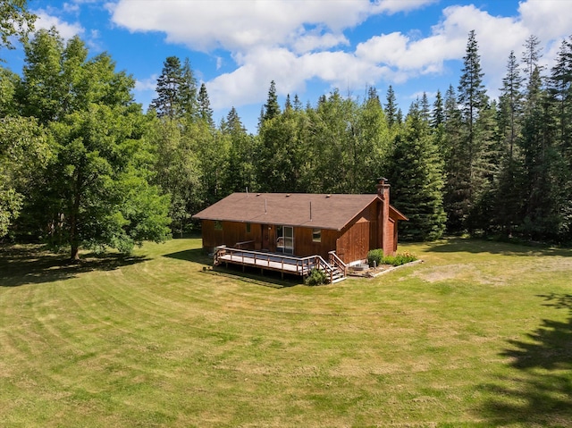 220 Ferndale Dr, Bigfork, MT 59911 - rear view of house featuring a deck, a chimney, a lawn, and a view of trees