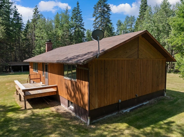 220 Ferndale Dr, Bigfork, MT 59911 - view of property exterior featuring a chimney, a lawn, a deck, and roof with shingles