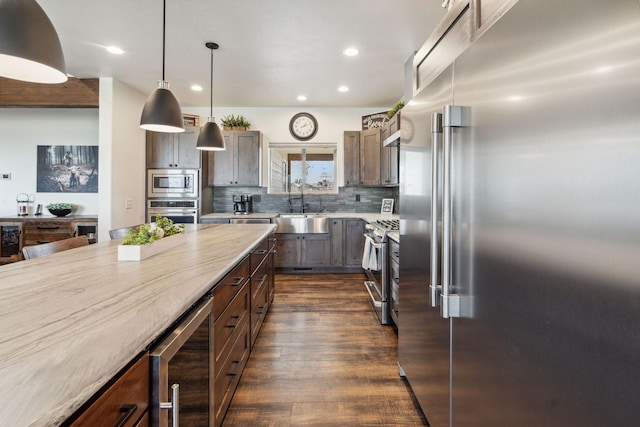 2650 W Valley Dr, Kalispell, MT 59901 - kitchen featuring a sink, decorative backsplash, dark wood-type flooring, wall chimney range hood, and stainless steel appliances