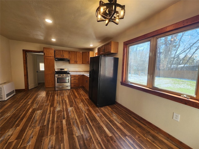 105 Stapp Ln, Darby, MT 59829 - kitchen featuring baseboards, black fridge, under cabinet range hood, dark wood-type flooring, and stainless steel range with gas cooktop