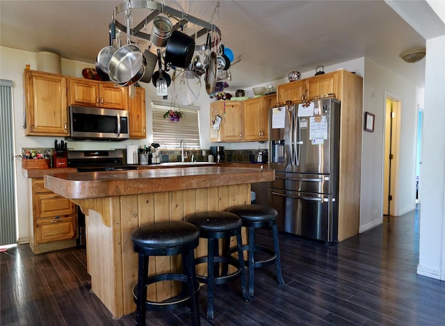 261 Locust Ln, Seeley Lake, MT 59868 - kitchen featuring appliances with stainless steel finishes, dark wood-style flooring, a breakfast bar, a sink, and a center island