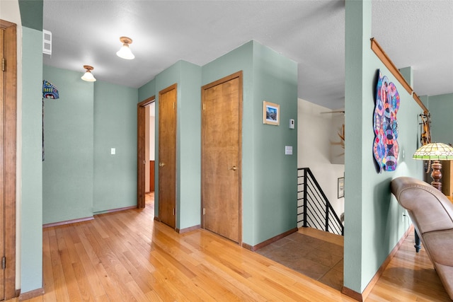 hall featuring baseboards, an upstairs landing, and wood finished floors