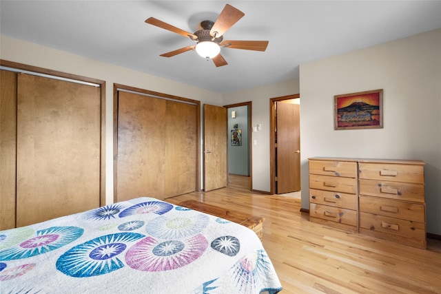 bedroom featuring light wood-style flooring, two closets, and ceiling fan