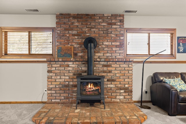 details featuring visible vents, a wood stove, baseboards, and carpet floors