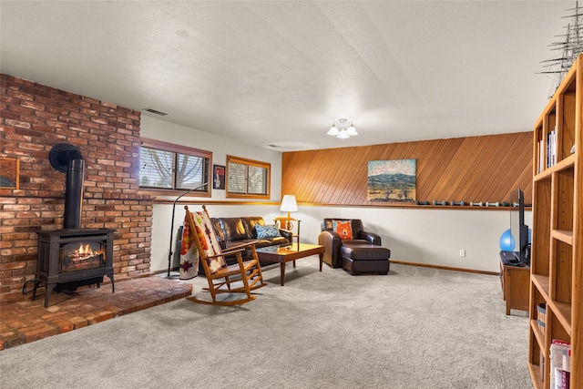 living area featuring a wood stove, baseboards, carpet flooring, and visible vents