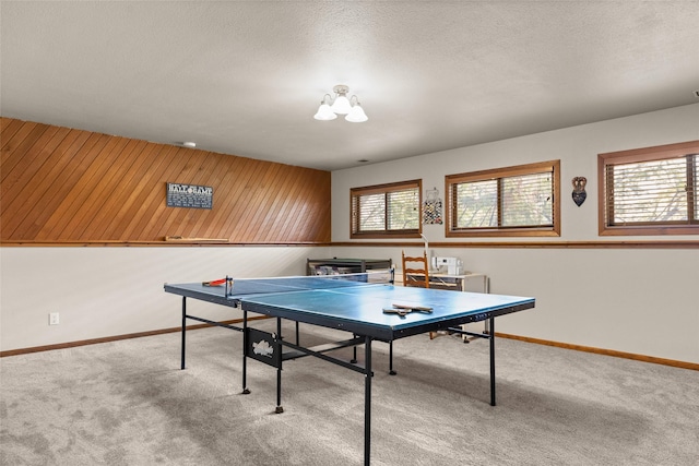 recreation room featuring a textured ceiling, carpet flooring, and baseboards