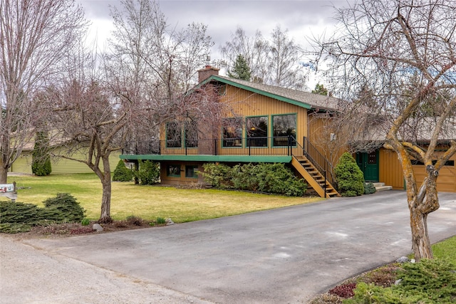 view of front facade with a chimney, driveway, a front lawn, and stairway