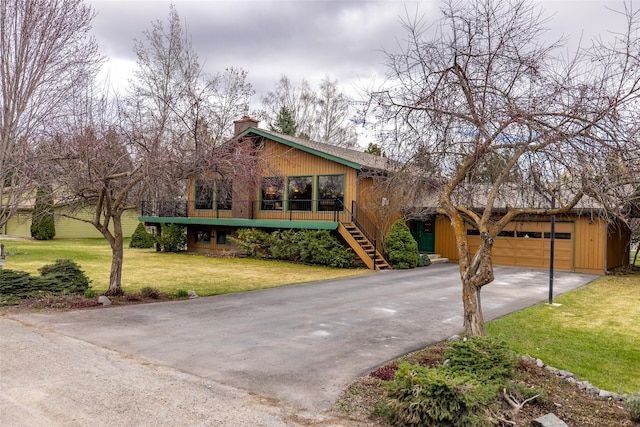 rustic home with a chimney, aphalt driveway, stairs, a front yard, and a garage