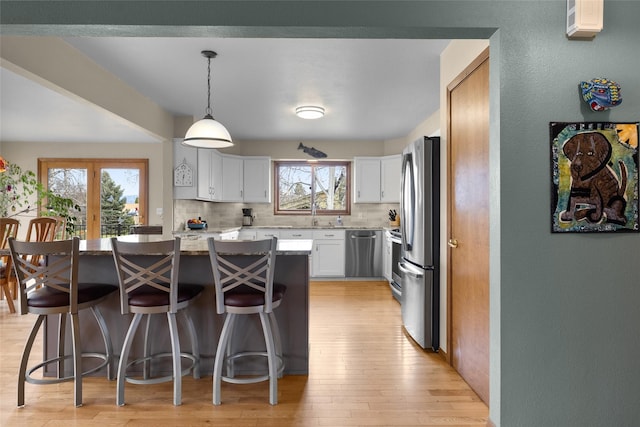 kitchen featuring tasteful backsplash, a breakfast bar, light stone counters, light wood-style floors, and appliances with stainless steel finishes