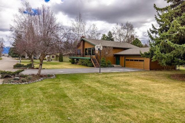 view of front of home with a garage, a chimney, stairs, a front lawn, and driveway