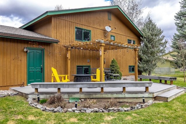 rear view of property featuring a wooden deck, a lawn, and a pergola