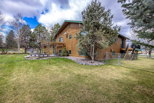 rear view of house featuring a yard, fence, and a gate