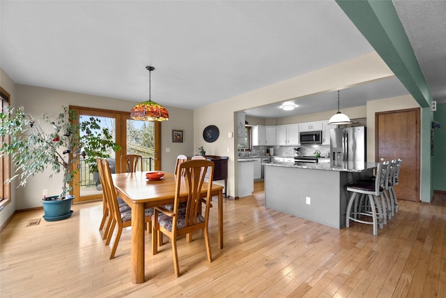 dining room featuring light wood-style flooring and visible vents