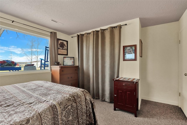 carpeted bedroom featuring visible vents, baseboards, and a textured ceiling
