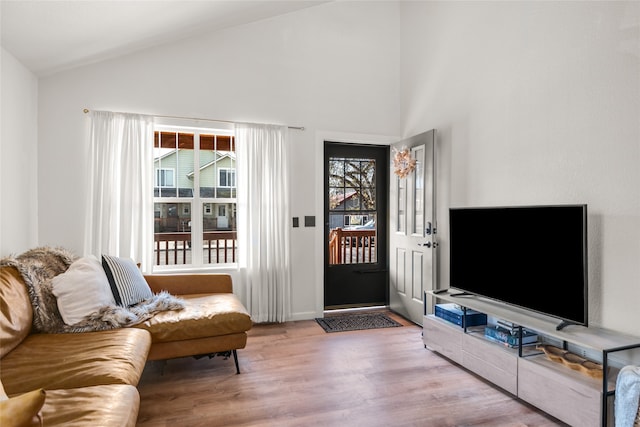 living area featuring wood finished floors, high vaulted ceiling, and baseboards