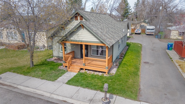 view of front of home featuring covered porch, roof with shingles, and a front lawn