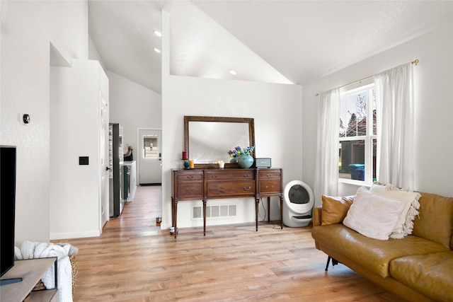 sitting room with lofted ceiling, light wood-type flooring, and baseboards