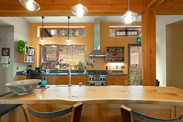 kitchen with stainless steel stove, open shelves, butcher block counters, wall chimney exhaust hood, and a sink