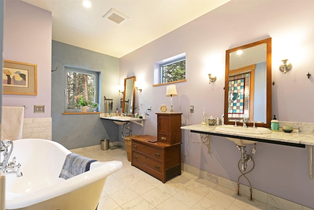 bathroom featuring a soaking tub, a sink, visible vents, and a healthy amount of sunlight