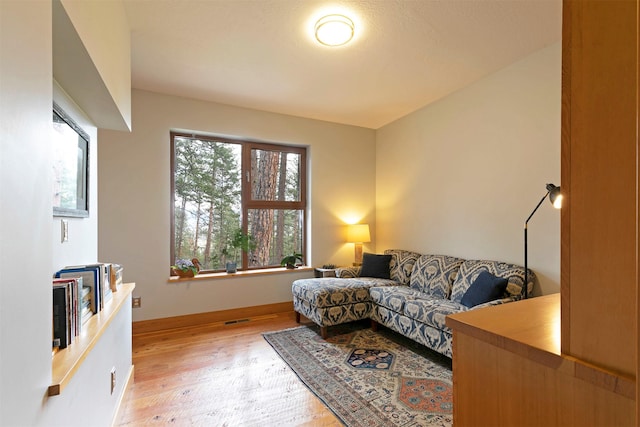 living area with light wood-style floors, baseboards, and visible vents