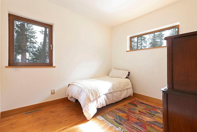 bedroom featuring visible vents, baseboards, and wood finished floors