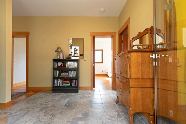 hallway with stone finish floor and baseboards