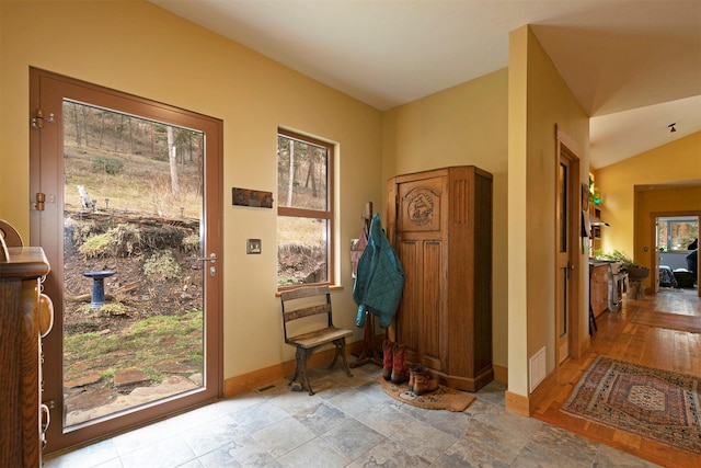entryway with baseboards, vaulted ceiling, and visible vents