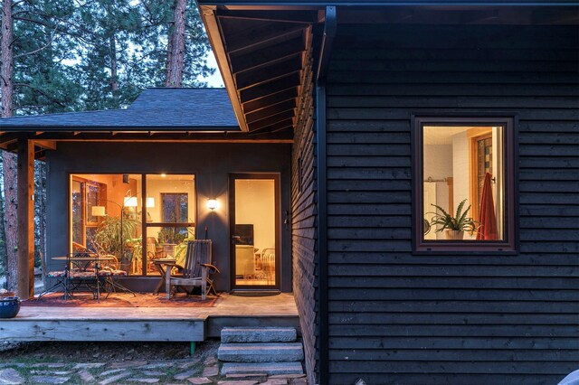 back of property featuring a wooden deck and roof with shingles