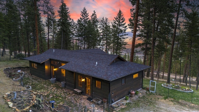 back of property at dusk featuring roof with shingles