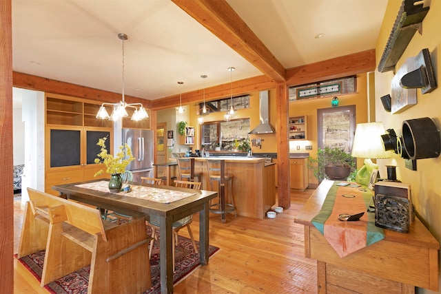 dining area featuring beam ceiling, light wood finished floors, and a chandelier