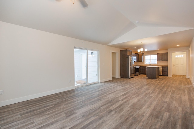 327 Meadow View Loop, East Helena, MT 59635 - unfurnished living room with light wood-style floors, ceiling fan with notable chandelier, baseboards, and lofted ceiling