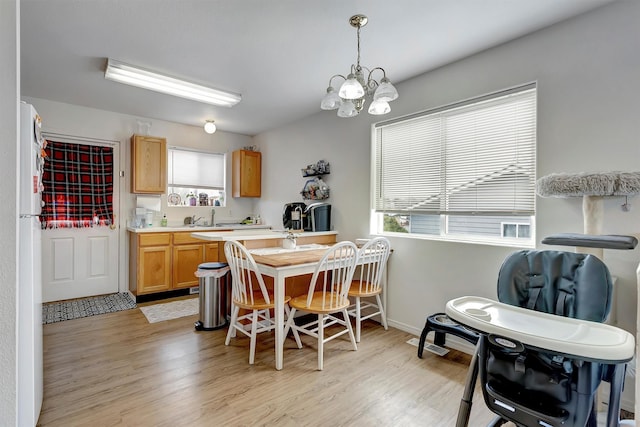 kitchen with freestanding refrigerator, a chandelier, light countertops, decorative light fixtures, and light wood finished floors