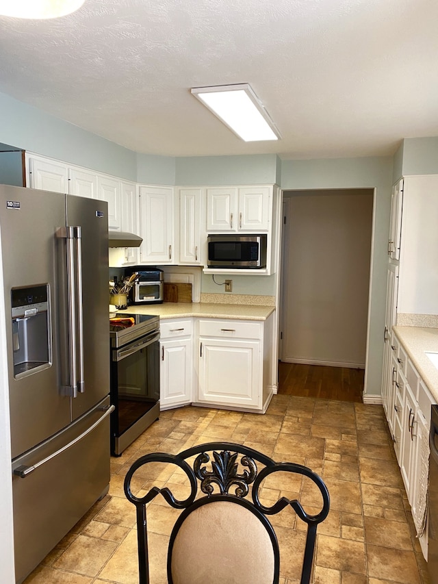 1405 2ND W Hill Dr, Great Falls, MT 59404 - kitchen featuring appliances with stainless steel finishes, light countertops, white cabinets, stone tile flooring, and under cabinet range hood