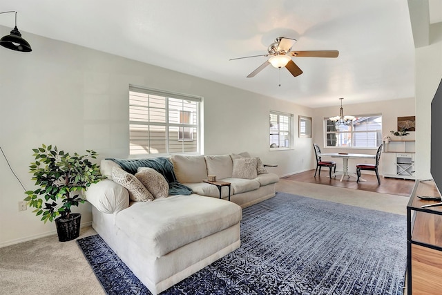 living area with baseboards and ceiling fan with notable chandelier