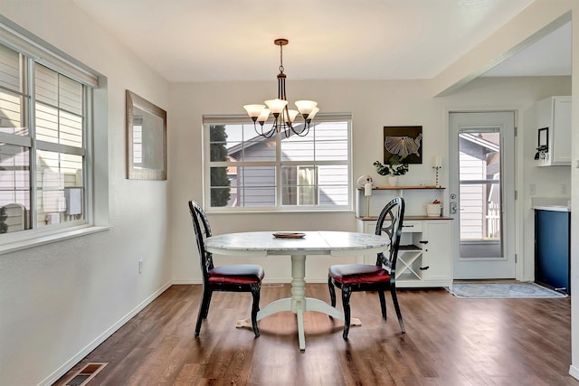 dining area featuring dark wood-type flooring, an inviting chandelier, baseboards, and visible vents