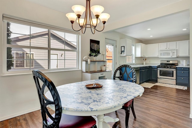 dining space with baseboards, recessed lighting, a chandelier, and wood finished floors